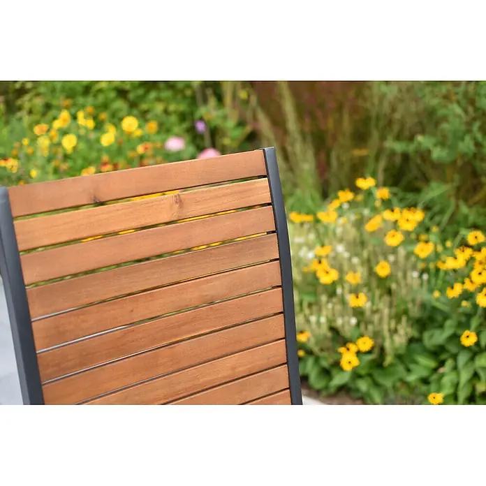 Merxx Gartentisch-Set Santorin - Gesamtumfang: 5 -tlg., Aluminium/Akazie, Klappbar - Rückenlehne eines Holzstuhls mit dunklem Metallrahmen im Garten.