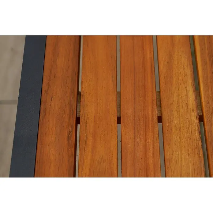 Merxx Gartentisch-Set Tilos - Gesamtumfang: 5 -tlg., Aluminium/Akazie, Klappbar - Nahaufnahme einer orange-braunen Holzlamellenfläche, links von einem dunkelgrauen Metallrahmen begrenzt.