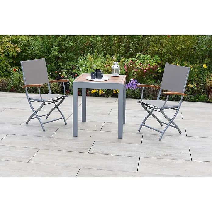 Merxx Gartentisch-Set Naxos - Gesamtumfang: 3 -tlg., Aluminium/Akazie/Textil, Klappbar - Outdoor-Esstischgarnitur mit grauem Tischgestell, Holzplatte und zwei grauen Stoffstühlen mit Holzarmlehnen auf einer Terrasse.