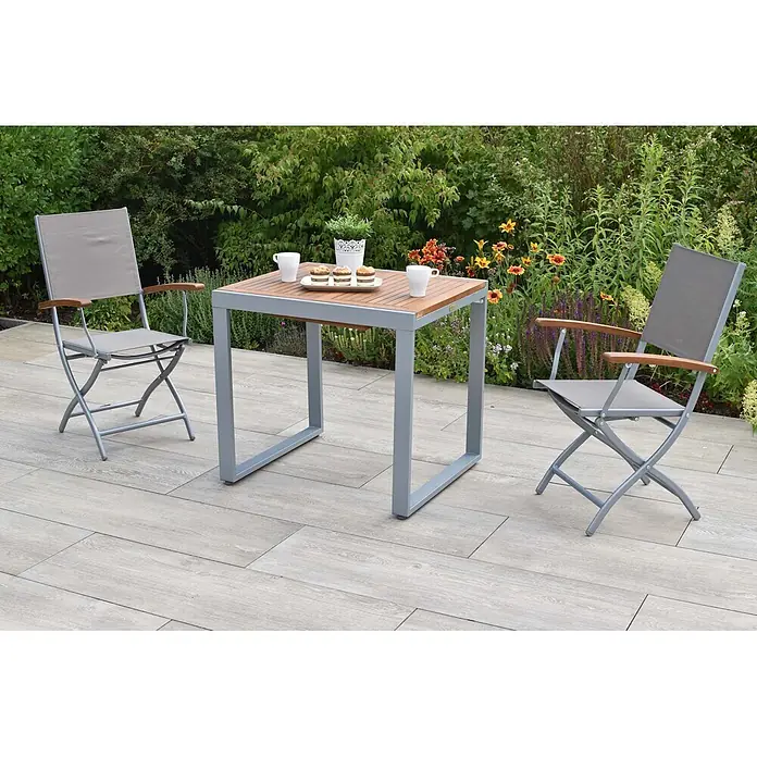 Merxx Gartentisch-Set Naxos - Gesamtumfang: 3 -tlg., Aluminium/Akazie/Textil, Klappbar - Graues Metall- und Holz-Terrassenset mit zwei Klappstühlen auf gefliester Terrasse. Tisch mit Tassen und Cupcakes.
