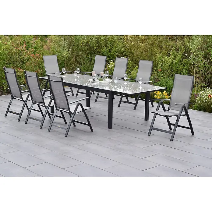 Merxx Gartentisch-Set Carrara - Gesamtumfang: 9 -tlg., L x B x H: 300 x 110 x 75 cm, Aluminium/Textil, Klappbar - Ein Outdoor-Esstischset mit grauem Glastisch und passenden grauen Mesh-Stühlen auf einer Terrasse umgeben von Gartengrün.