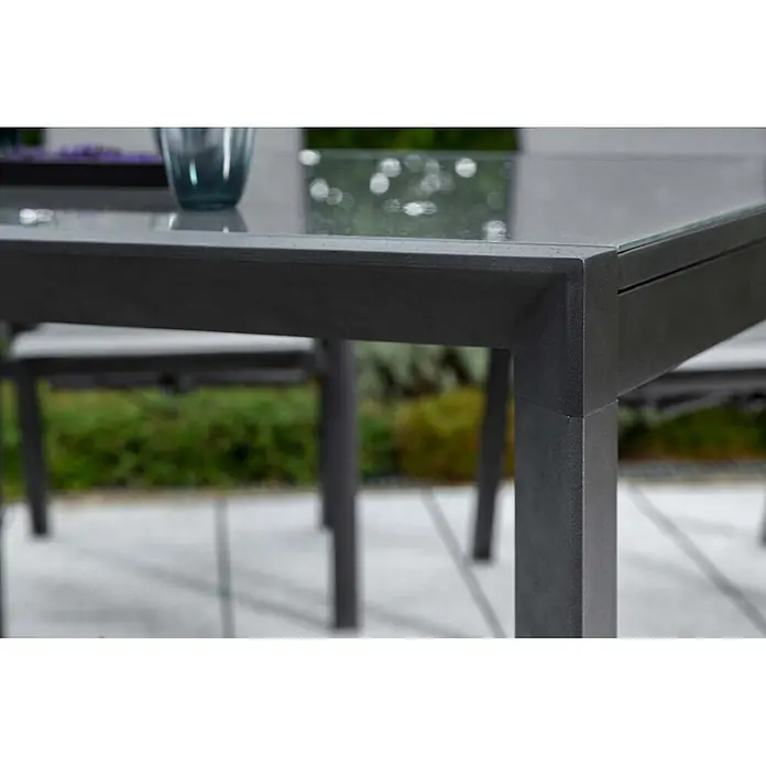 Merxx Gartentisch-Set Carrara - Gesamtumfang: 9 -tlg., L x B x H: 300 x 110 x 75 cm, Aluminium/Textil, Klappbar - Nahaufnahme eines dunkelgrauen Metall-Gartentisches mit Glasplatte auf einer Terrasse.
