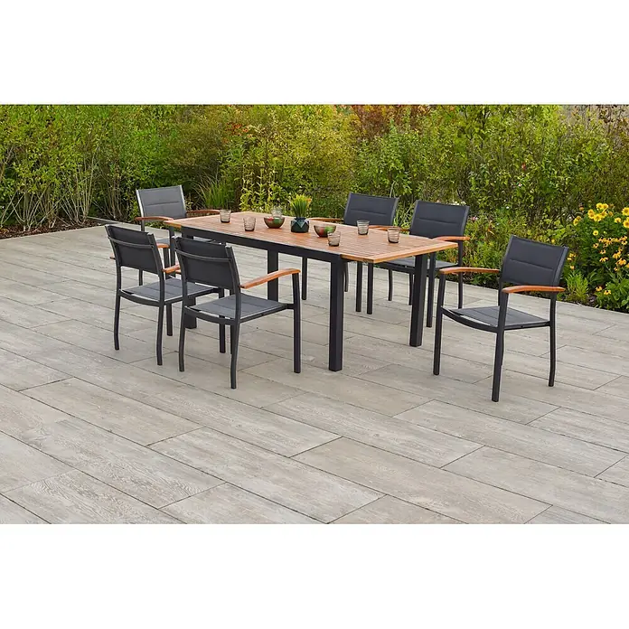Merxx Gartentisch-Set Paxos - Gesamtumfang: 7 -tlg., L x B x H: 200 x 90 x 75 cm, Aluminium/Textil/Akazie, Stapelbar - Outdoor-Essgruppe mit Holztisch und dunklen Beinen sowie sechs Stühlen mit dunklen Netzsitzen und Holzarmlehnen auf einer Terrasse.