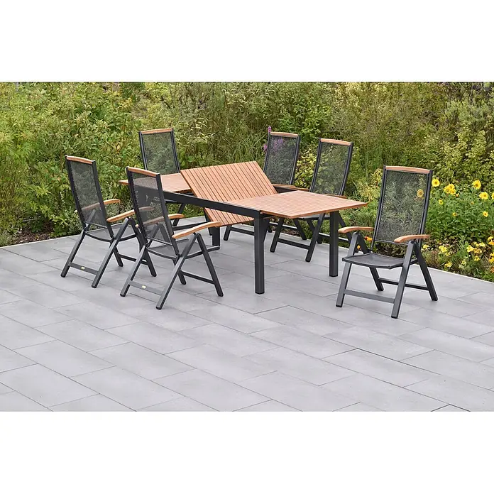Merxx Gartentisch-Set Tilos - Gesamtumfang: 7 -tlg., Aluminium/Akazie, Klappbar - Eine Outdoor-Essgruppe mit Latten-Holztisch und sechs schwarzen Metallstühlen mit Holzarmlehnen auf einer Terrasse.