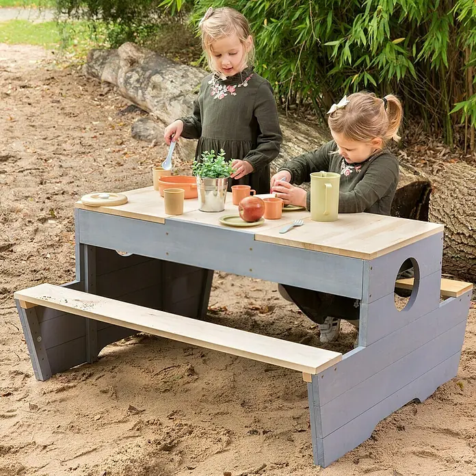 Muddy Buddy Kinder-Picknicktisch Creator - L x B x H: 100 x 90 x 50 cm, Holz, Natur/Wolkengrau - Kindersitzgruppe im Freien mit Tisch und Bänken in Grau und Naturholz mit spielenden Kindern.