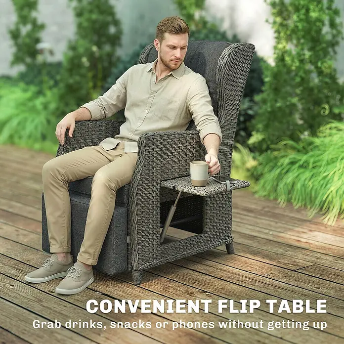 Outsunny Garten-Loungesessel - PE-Rattan, Metall, Kationischer Stoff, Schaumstoff, PP-Baumwolle, Rückenlehne verstellbar, Dunkelgrau, B x T x H: 58 x 55 x 98,5 cm - Ein Mann entspannt in einem grauen Outdoor-Sessel im Rattan-Stil mit integriertem Klapptisch, eine Tasse neben seinem Telefon auf dem Tisch haltend.