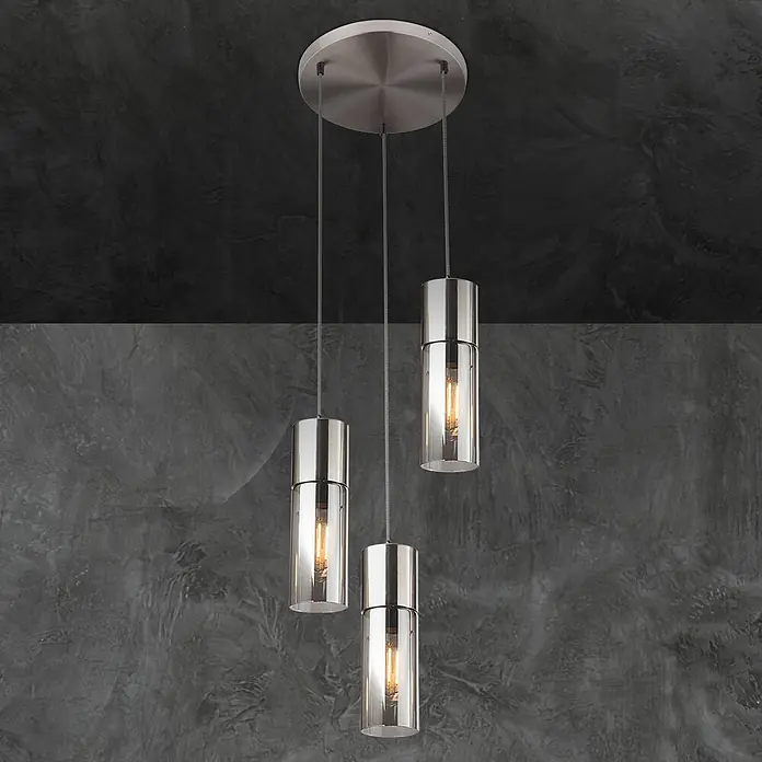 Globo Pendelleuchte Annika - 25 W, Ø x H: 30 x 150 cm - Drei moderne Pendelleuchten aus gebürstetem Metall und Klarglas vor einer dunklen Betonwand.