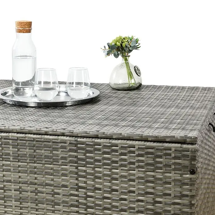 Juskys Garten-Aufbewahrungsbox Ikaria - grau, Kunststoff - Graue Rattan-Aufbewahrungsbox, die als Tisch dient, mit Getränken und Blumen darauf.
