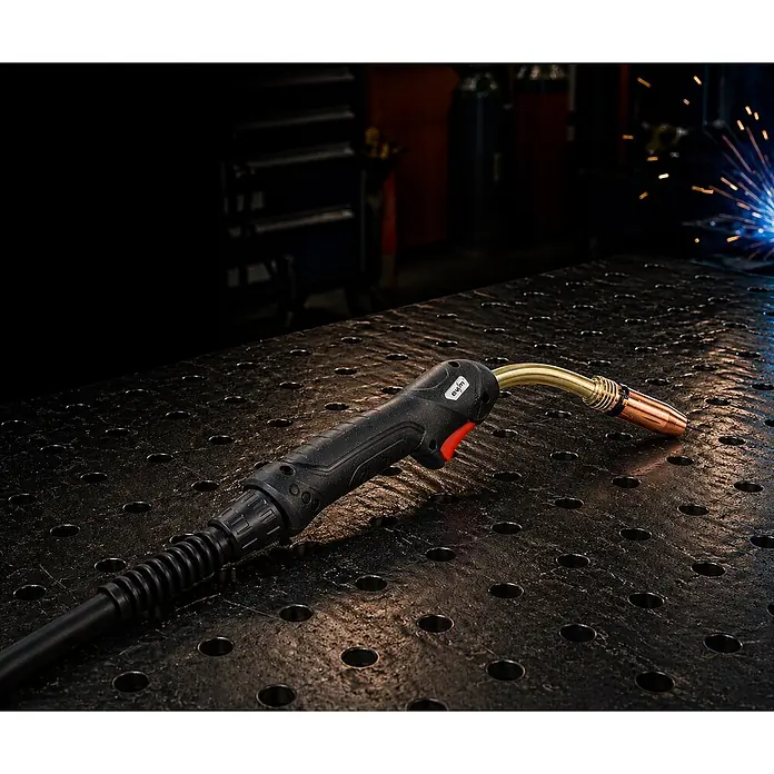 EWM MIG/MAG-Schweißbrenner UM 401 wassergekühlt 5m - 5 m - Eine schwarze MIG-Schweißpistole mit Messinghals und Kupferdüse liegt auf einer Metallwerkbank, mit Schweißfunken im Hintergrund.