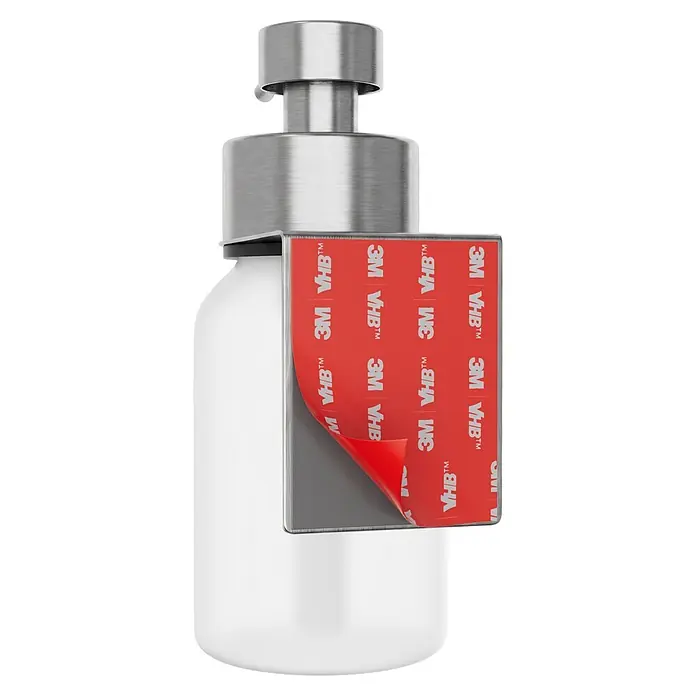 Camargue Antwerpen Seifenspender - Edelstahl, Edelstahl, Für die Wand - Weiße Flasche mit silbernem Pumpspender und einem grauen Aufsatz mit teilweise abgezogener roter 3M VHB Klebebandabdeckung.