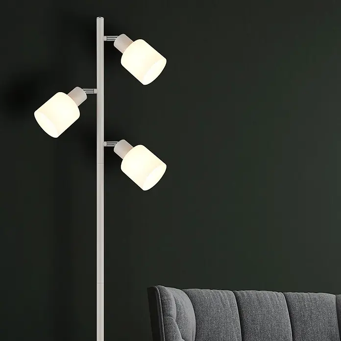 Globo Stehleuchte Trent - 25 W, Höhe: 1.610 mm, E14 - Weiße dreiflammige Stehleuchte mit beleuchteten, verstellbaren Köpfen, neben einem grauen Sofa platziert.