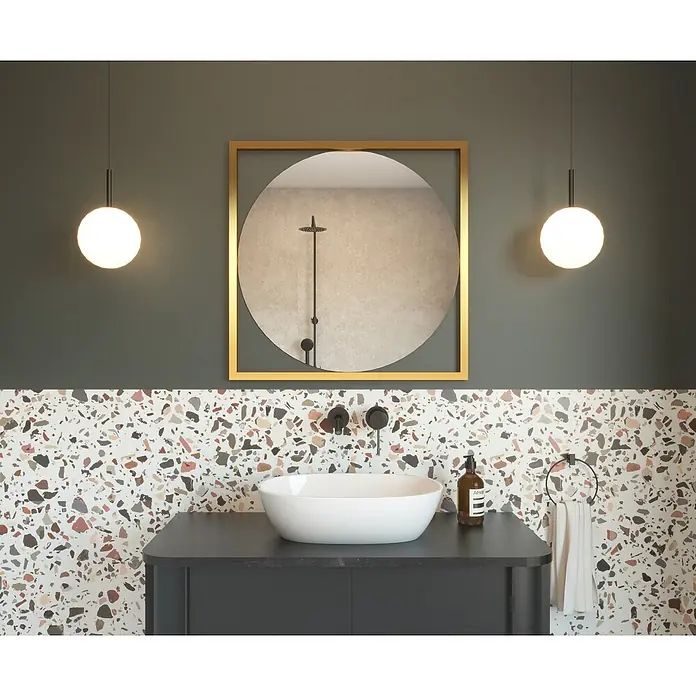Cordia Rahmenspiegel - 63,5 x 63,5 cm, Gold, Aluminium - Modernes Badezimmer mit einem weißen Aufsatzwaschbecken auf einem schwarzen Waschtisch, schwarzer Wandarmatur und goldgerahmtem Spiegel über Terrazzofliesen.
