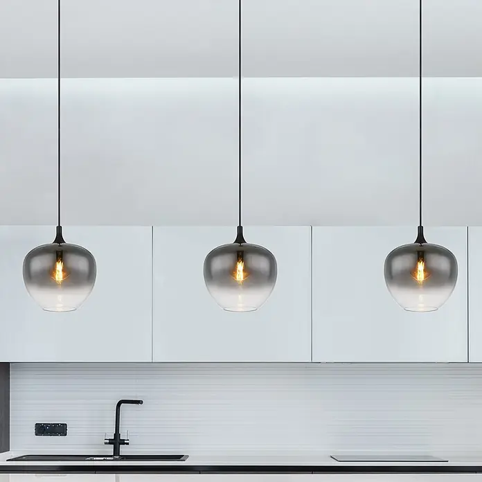 Globo Pendelleuchte Maxy - 60 W, Ø x H: 29 x 120 cm, 1-Strahlig, E27 - Drei Pendelleuchten mit Rauchglas-Schirmen und schwarzen Kabeln hängen über einer modernen Küchenzeile mit Spüle.