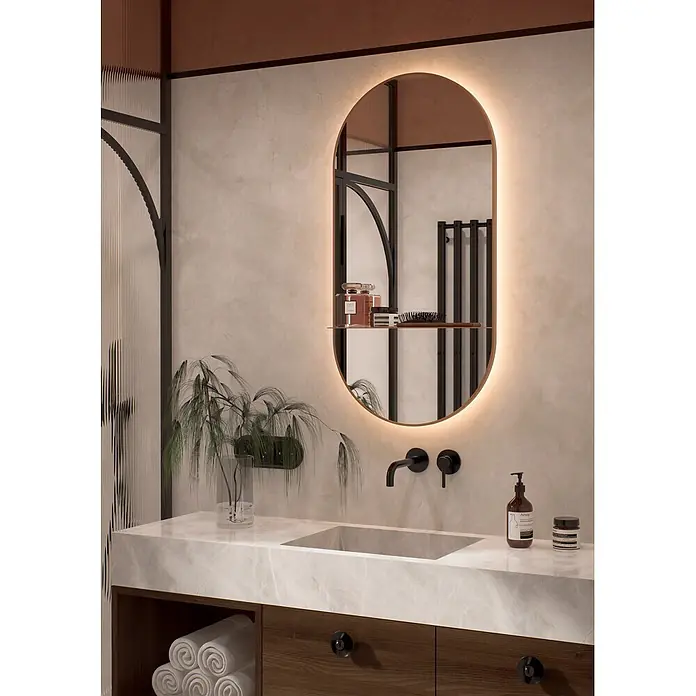 Cordia Lichtspiegel - 50 x 100 cm, Kupfer - Marmor-Waschtisch mit integriertem Waschbecken, dunklem Holzschrank und schwarzer Armatur unter hinterleuchtetem Ovalspiegel.