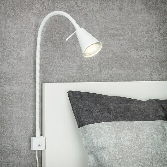 Briloner Foco de pared LED para cama Comfort Light - Blanco, 4 W - Primer plano de una lámpara de lectura blanca ajustable montada en un cabecero blanco, que ilumina una almohada de rayas grises.