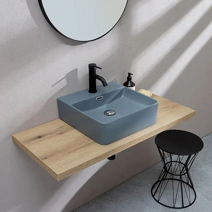 Kiamami Valentina Aufsatzwaschbecken - 420 x 420 cm, Grau - Mattblau-graues rechteckiges Keramikwaschbecken mit schwarzem Wasserhahn auf einem hellen Holz-Schwimmregal.