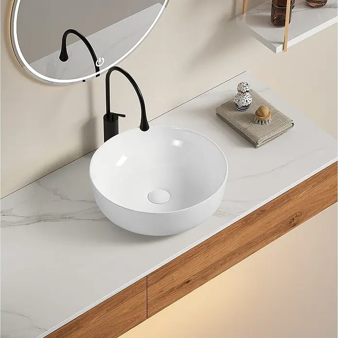 Kiamami Valentina Aufsatzwaschbecken - 415 x 415 cm, Weiß - Modernes weißes, rundes Aufsatzwaschbecken mit schwarzem, hohem Wasserhahn und Seifenspender auf einer Marmor-Arbeitsplatte.