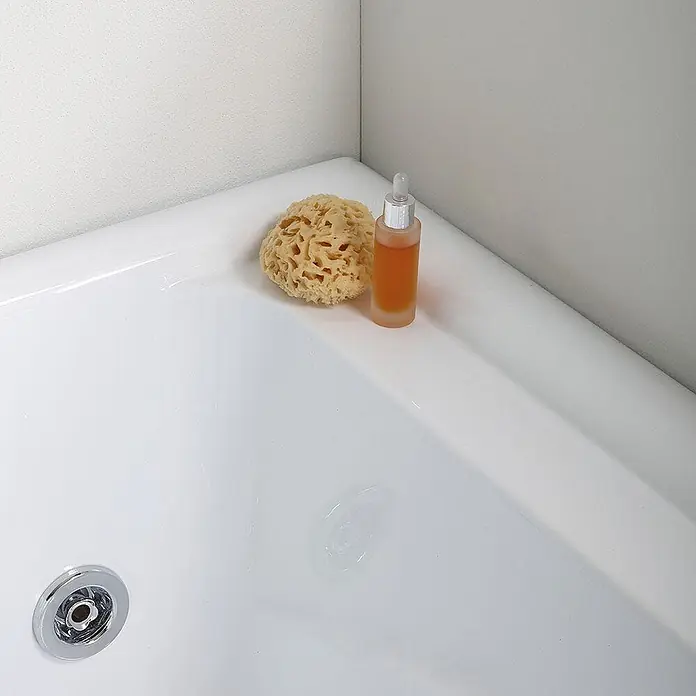 Kiamami Valentina Badewanne - 1.700 x 780 cm, ABS-Kunststoff und Acryl, Weiß - Naturschwamm und Pipettenflasche mit Orangenöl in einer weißen Badewanne.