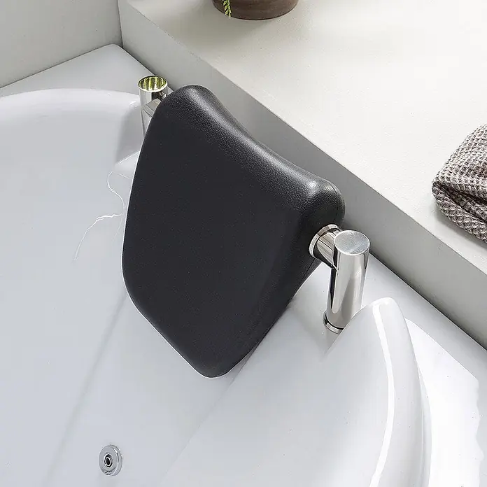 Kiamami Valentina Badewanne - 1.700 x 780 cm, ABS-Kunststoff und Acryl, Weiß - Ergonomische schwarze Badewannen-Kopfstütze, mit polierten Chromarmaturen an einer weißen Wanne befestigt.