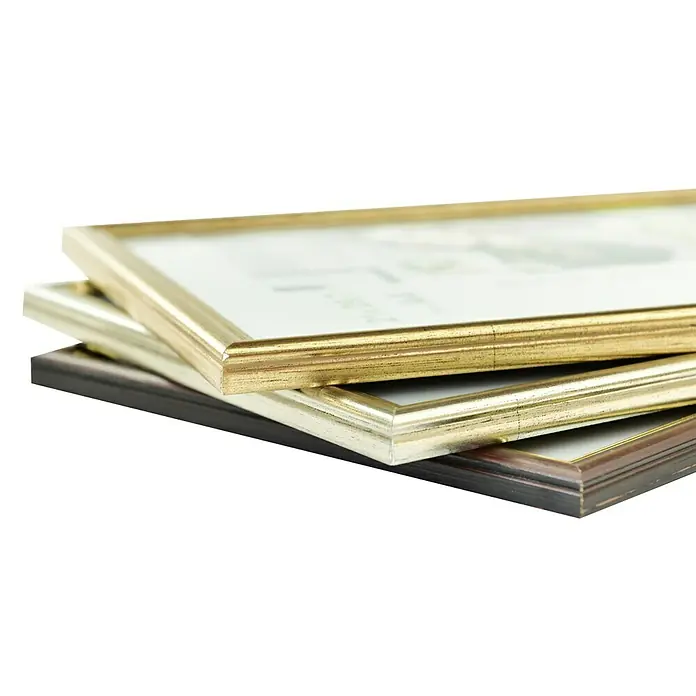 Nielsen Holzrahmen Ascot - 13 x 18 cm, Silber, Glas - Eine Nahaufnahme von drei Bilderrahmen in Gold-, Silber- und Brauntönen, die gestapelt liegen. Ideal für die Präsentation von Fotos und Kunstwerken.