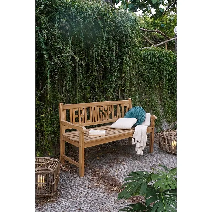 Garden Pleasure Gartenbank Lieblingsplatz - B x T x H: 150 x 63 x 89 cm, Teak, Braun - Hölzerne Gartenbank mit "LIEBLINGSPLATZ"-Rückenlehne, mit Kissen und Decke in Gartenumgebung.