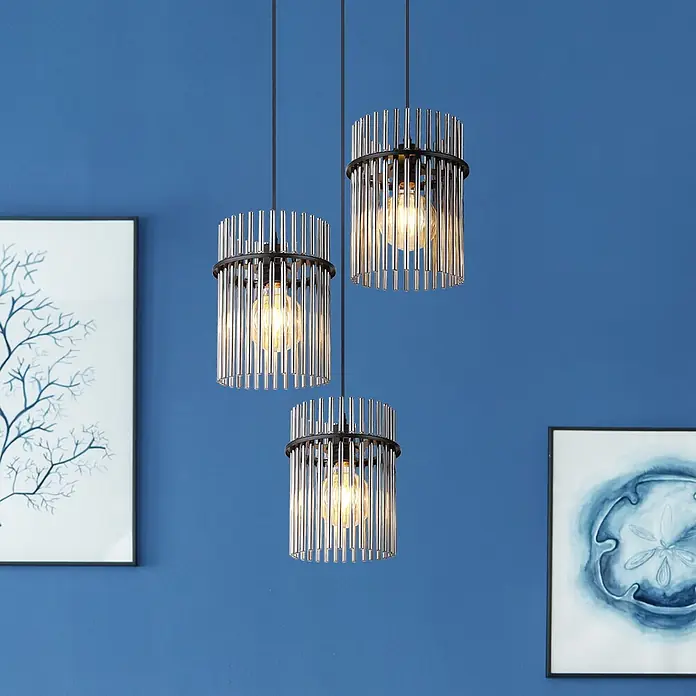 Globo Pendelleuchte Gorley - L x B x H: 800 x 200 x 1.400 mm - Drei Pendelleuchten mit schwarzen Rahmen und Chromstäben, die warmes Licht abgeben, hängen vor einer blauen Wand.