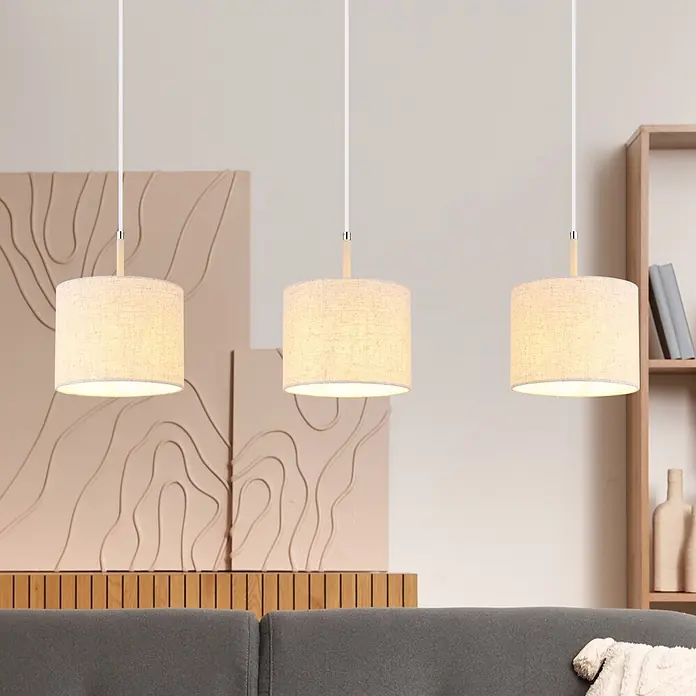 Globo Pendelleuchte Deleon - 40 W, L x B x H: 90 x 20 x 120 cm, Creme, E27 - Drei Pendelleuchten mit zylindrischen, hellen Stoffschirmen und Holzdetails hängen in einem modernen Wohnraum.