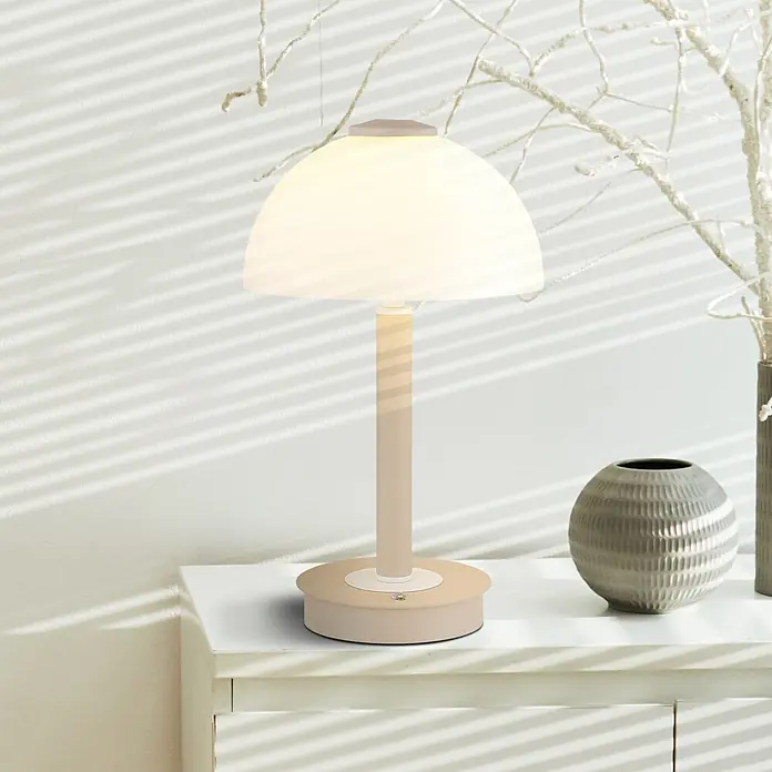 Globo LED-Tischleuchte Uldin - 7 W, Warmweiß - Beige Tischlampe mit weißem Kuppelschirm auf einem weißen Beistelltisch, spendet warmes Licht im Raum.