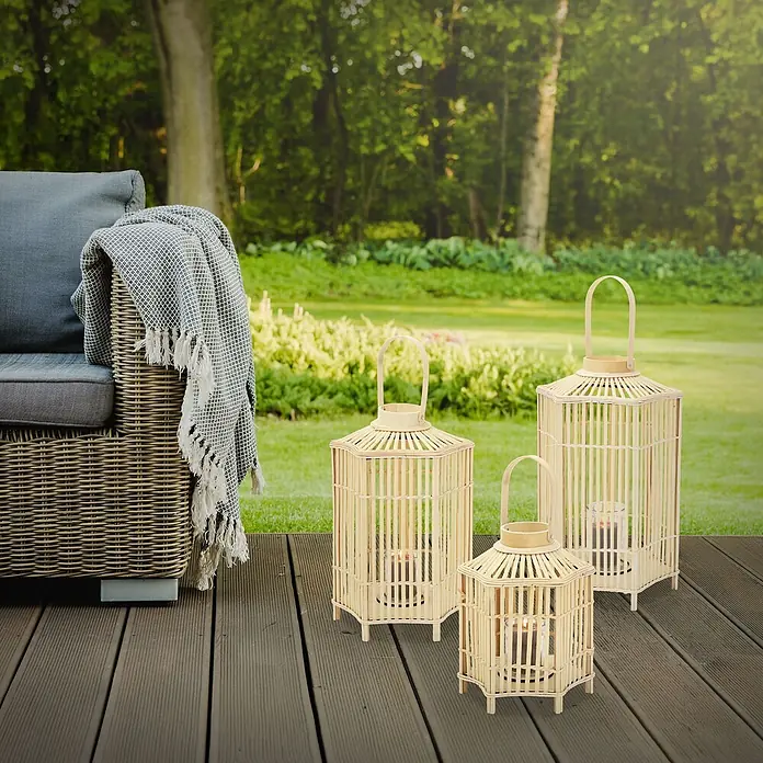 ECD Germany Windlicht Boho Bambus Laterne - Ø x H: 35 x 75 cm, Natur - Drei natürliche Bambus-Laternen in verschiedenen Größen mit brennenden Kerzen, auf einer Holzterrasse neben einem grauen Gartensofa.