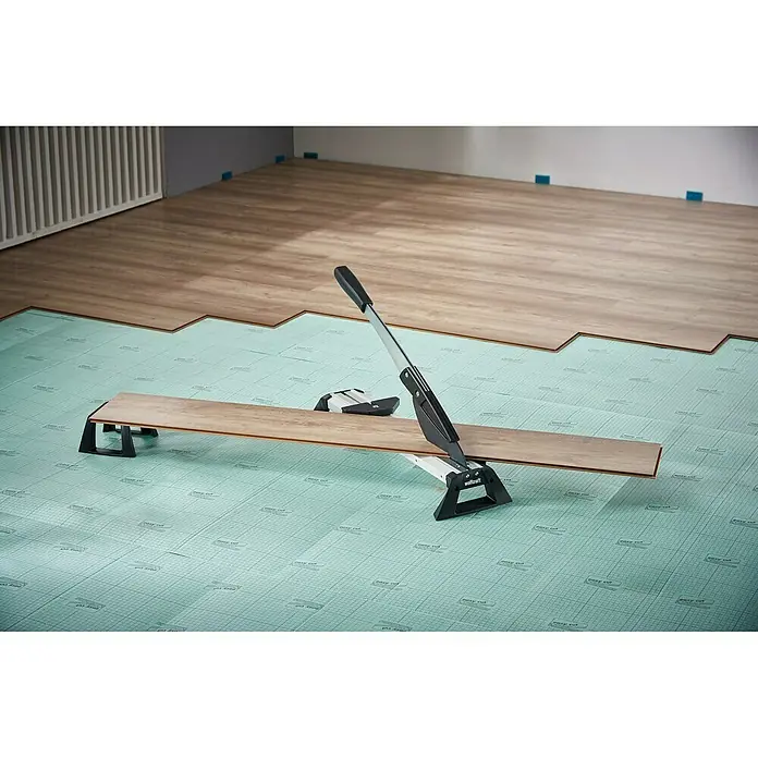 Wolfcraft Laminat- & Vinylschneider VLC 800 - Schnittbreite: 465 mm, Aluminium - Bild von einem Laminatschneider, der ein Laminatstück schneidet, das auf einer grünen Unterlage liegt.