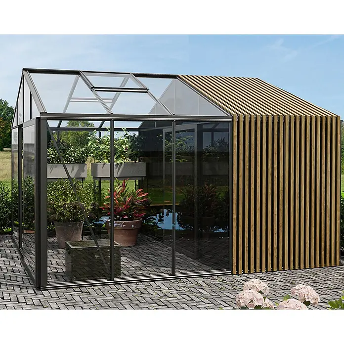 Bloomcabin Gewächshaus Aluminium Klassik mit Accoya-Fusion und mittlerem integrierten Stauraum - Außenmaß inkl. Dachüberstand (B x T): 235 x 384 cm, Material Seitenwand: Glas, 4 mm, Schwarz - Modernes Gewächshaus mit Glaspaneelen, dunklem Rahmen und natürlichen Holzlatten auf einer gepflasterten Terrasse mit Pflanzen.