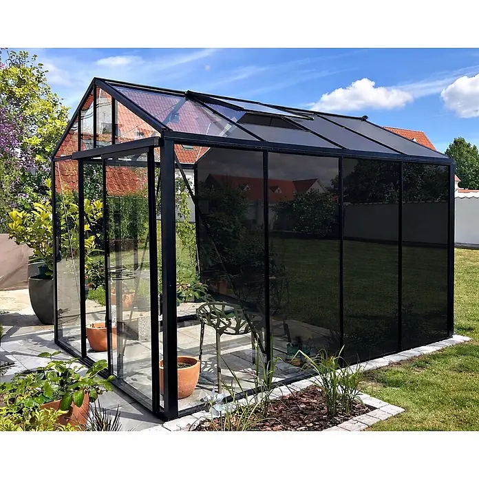 Bloomcabin Gewächshaus Aluminium Klassik mit mittlerem integrierten Stauraum - Außenmaß inkl. Dachüberstand (B x T): 235 x 309 cm, Material Seitenwand: Glas, 4 mm, Schwarz - Schwarz gerahmtes Gewächshaus mit klaren und reflektierenden Glasscheiben in einem sonnigen Garten.