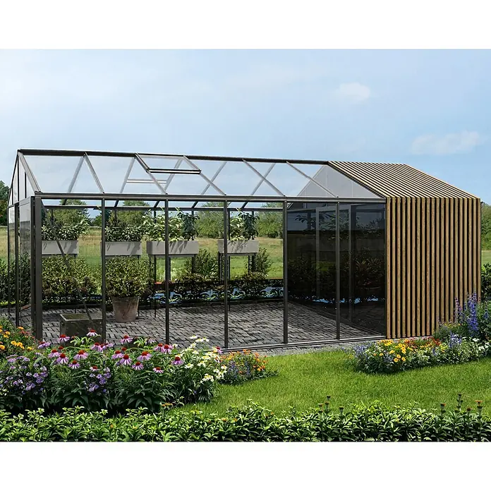 Bloomcabin Gewächshaus Aluminium Klassik mit Accoya-Fusion und mittlerem integrierten Stauraum - Außenmaß inkl. Dachüberstand (B x T): 235 x 608 cm, Material Seitenwand: Glas, 4 mm, Schwarz - Ein modernes Gewächshaus mit schwarzem Rahmen, Glaswänden und einer Holzlamellenverkleidung, eingebettet in einen Garten.