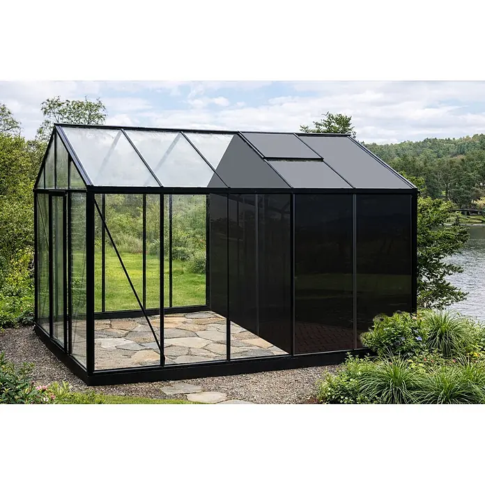 Bloomcabin Gewächshaus Aluminium Klassik mit mittlerem integrierten Stauraum - Außenmaß inkl. Dachüberstand (B x T): 235 x 384 cm, Material Seitenwand: Glas, 4 mm, Schwarz - Schwarzgerahmtes Gewächshaus mit klaren und dunklen undurchsichtigen Paneelen, innen Steinplattenboden, im Freien an einem See.