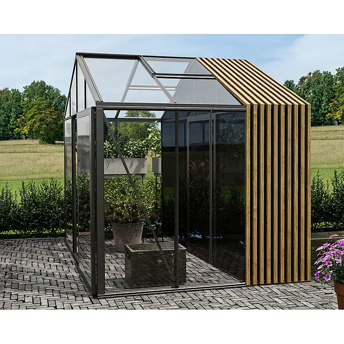 Bloomcabin Gewächshaus Aluminium Klassik mit Accoya-Fusion und kleinem integrierten Stauraum - Außenmaß inkl. Dachüberstand (B x T): 235 x 235 cm, Material Seitenwand: Glas, 4 mm, Schwarz - Modernes Gewächshaus mit dunklem Rahmen, Glaspaneelen und Holzlamellenseite auf gepflasterter Terrasse im Garten.
