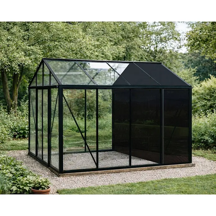 Bloomcabin Gewächshaus Aluminium Klassik mit kleinem integrierten Stauraum - Außenmaß inkl. Dachüberstand (B x T): 309 x 309 cm, Material Seitenwand: Glas, 4 mm, Schwarz - Ein modernes schwarzgerahmtes Gewächshaus mit Glas- und blickdichten Paneelen auf einem Kiesweg.