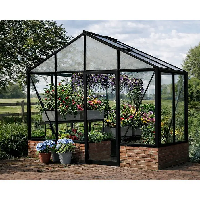 Bloomcabin Gewächshaus Aluminium für die Wandbasis - Außenmaß inkl. Dachüberstand (B x T): 309 x 160 cm, Material Seitenwand: Glas, 4 mm, Schwarz - Schwarzgerahmtes Gewächshaus mit Glaspaneelen und Ziegelsockel, gefüllt mit Pflanzen und Blumen in einem Garten.