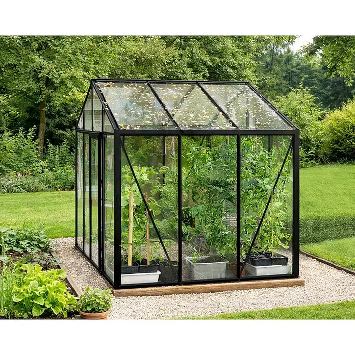 Bloomcabin Gewächshaus Aluminium Klassik - Außenmaß inkl. Dachüberstand (B x T): 309 x 235 cm, Material Seitenwand: Glas, 4 mm, Schwarz - Schwarzes Gewächshaus aus Glas mit Pflanzen, auf Kies in einem grünen Garten stehend.