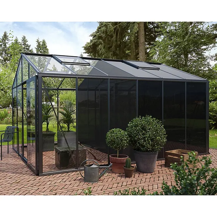 Bloomcabin Gewächshaus Aluminium Klassik mit großem integrierten Stauraum - Außenmaß inkl. Dachüberstand (B x T): 309 x 459 cm, Material Seitenwand: Glas, 4 mm, Schwarz - Großes dunkelgraues Gewächshaus mit klaren und schattierten Glaspaneelen auf einer Ziegelterrasse im Garten.