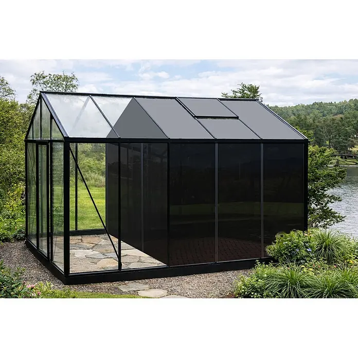 Bloomcabin Gewächshaus Aluminium Klassik mit großem integrierten Stauraum - Außenmaß inkl. Dachüberstand (B x T): 235 x 384 cm, Material Seitenwand: Glas, 4 mm, Schwarz - Schwarz gerahmtes Gewächshaus mit Glas- und dunklen Paneelen, Dachlüftern, an einem See gelegen.
