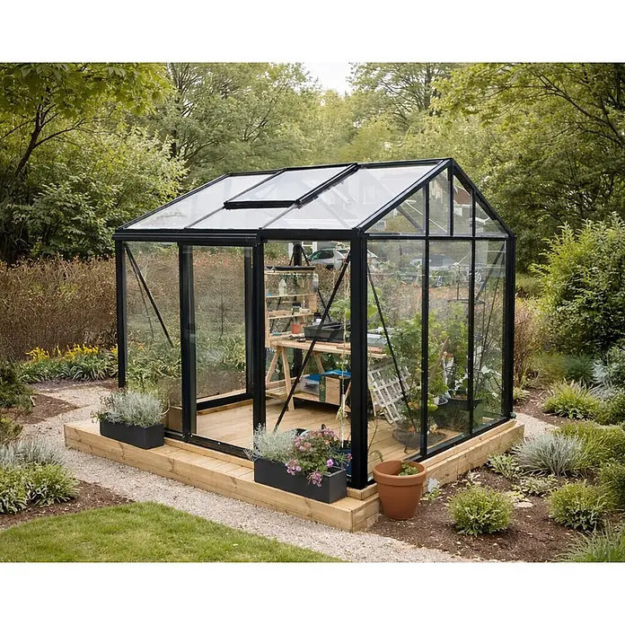 Bloomcabin Gewächshaus Aluminium Klassik - Außenmaß inkl. Dachüberstand (B x T): 235 x 235 cm, Material Seitenwand: Glas, 4 mm, Schwarz - Ein modernes Gewächshaus aus Glas mit schwarzem Rahmen und Pflanzen im Inneren, auf einem Holzsockel in einem üppigen Garten.