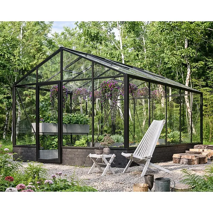 Bloomcabin Gewächshaus Aluminium für die Wandbasis - Außenmaß inkl. Dachüberstand (B x T): 309 x 384 cm, Material Seitenwand: Glas, 4 mm, Schwarz - Großes Gewächshaus mit schwarzem Glasrahmen und dunklem Ziegelsockel, mit Pflanzen gefüllt, in einem üppigen Garten mit Sitzgelegenheiten.