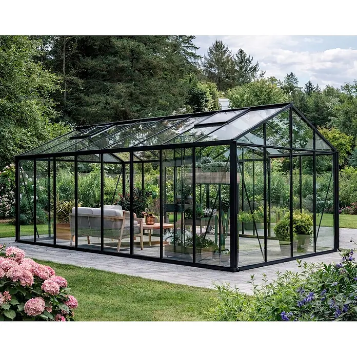 Bloomcabin Gewächshaus T-Modell Orangerie - Außenmaß inkl. Dachüberstand (B x T): 459 x 608 cm, Material Seitenwand: Glas, 4 mm, Schwarz - Großes modernes Gewächshaus mit schwarzem Rahmen, Glaswänden, Sitzgelegenheiten und Pflanzen in einem Garten.