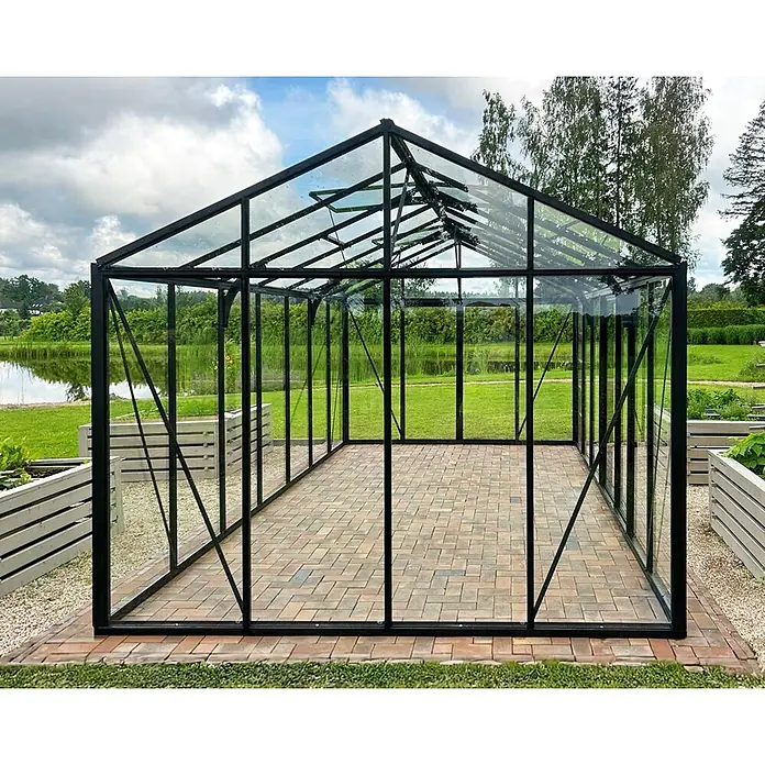 Bloomcabin Gewächshaus Aluminium Klassik - Außenmaß inkl. Dachüberstand (B x T): 309 x 533 cm, Material Seitenwand: Glas, 4 mm, Schwarz - Großes Gewächshaus mit schwarzem Rahmen und Glas, gepflastertem Boden, in einem Garten mit Hochbeeten.