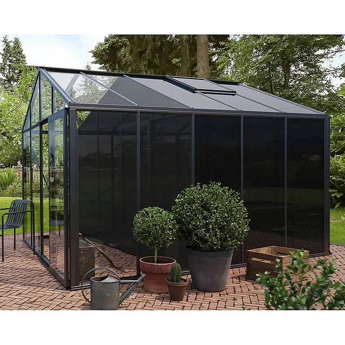 Bloomcabin Gewächshaus Aluminium Klassik mit großem integrierten Stauraum - Außenmaß inkl. Dachüberstand (B x T): 309 x 384 cm, Material Seitenwand: Glas, 4 mm, Schwarz - Modernes schwarzes Gewächshaus mit Glas- und blickdichten Paneelen auf einer Ziegelterrasse im Garten.