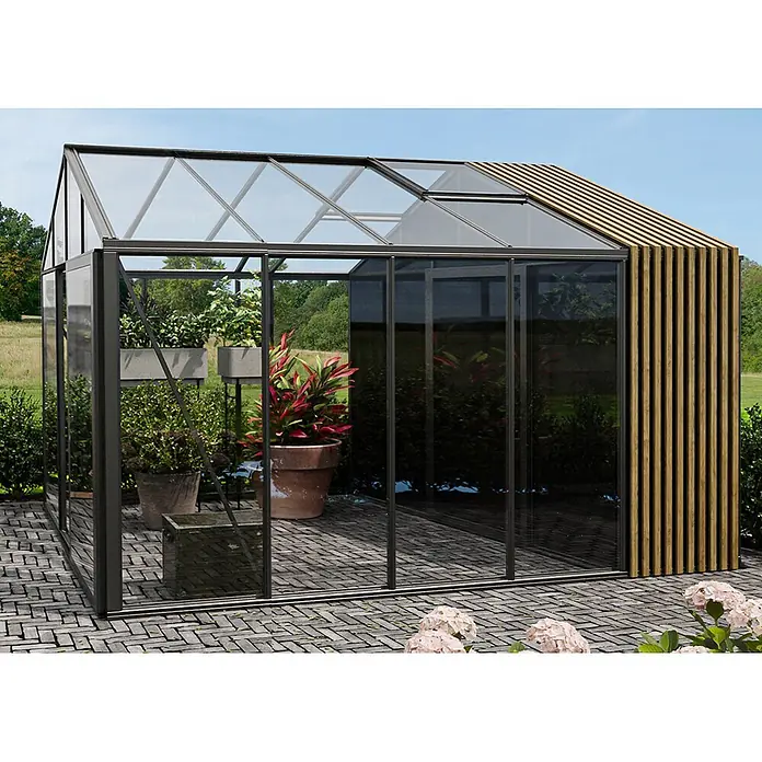 Bloomcabin Gewächshaus Aluminium Klassik mit Accoya-Fusion und kleinem integrierten Stauraum - Außenmaß inkl. Dachüberstand (B x T): 235 x 384 cm, Material Seitenwand: Glas, 4 mm, Schwarz - Modernes Gewächshaus mit dunklem Metallrahmen, Klarglaspaneelen und einer Holzlamellenwand, auf einer gepflasterten Terrasse mit Pflanzen.