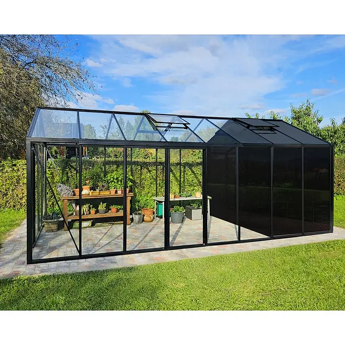 Bloomcabin Gewächshaus Aluminium Klassik mit mittlerem integrierten Stauraum - Außenmaß inkl. Dachüberstand (B x T): 309 x 608 cm, Material Seitenwand: Glas, 4 mm, Schwarz - Schwarz gerahmtes Gewächshaus mit klaren und dunklen Paneelen, geöffneten Dachlüftern und Pflanzen.