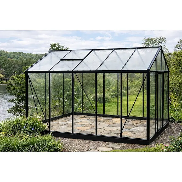 Bloomcabin Gewächshaus Aluminium Klassik - Außenmaß inkl. Dachüberstand (B x T): 235 x 384 cm, Material Seitenwand: Glas, 4 mm, Schwarz - Großes Gewächshaus mit schwarzem Rahmen und Glas, Steinboden und Dachlüftern, in einem Garten am See.