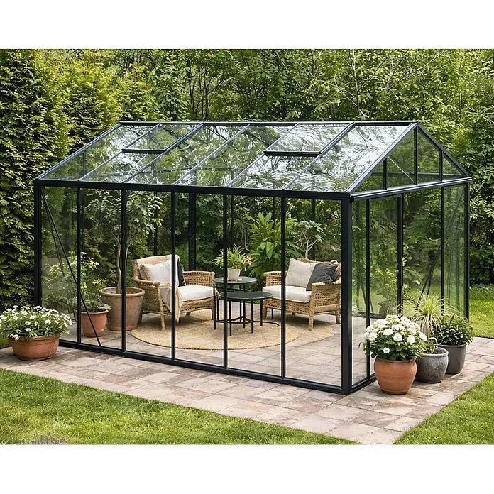 Bloomcabin Gewächshaus Aluminium Klassik - Außenmaß inkl. Dachüberstand (B x T): 235 x 459 cm, Material Seitenwand: Glas, 4 mm, Schwarz - Schwarz gerahmtes Glasgewächshaus im Garten, mit Korbsesseln und Topfpflanzen als elegante Wohnfläche im Freien eingerichtet.