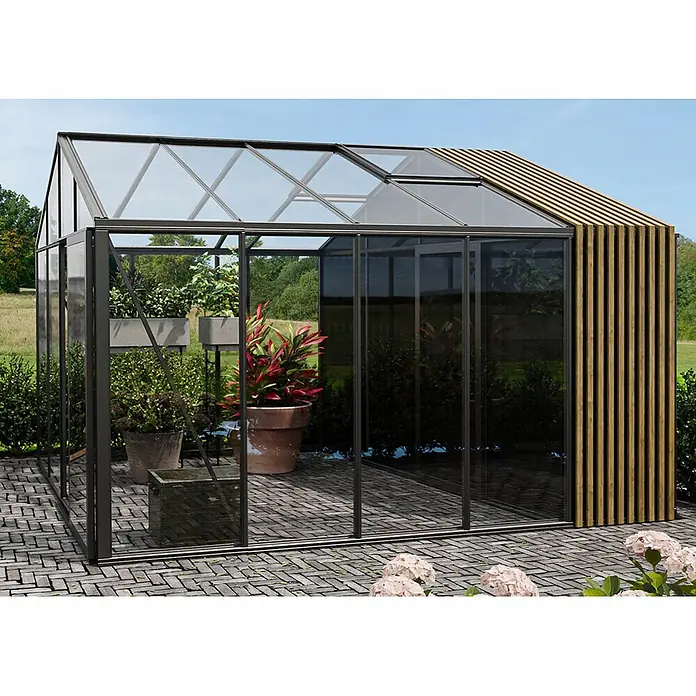 Bloomcabin Gewächshaus Aluminium Klassik mit Accoya-Fusion und kleinem integrierten Stauraum - Außenmaß inkl. Dachüberstand (B x T): 309 x 384 cm, Material Seitenwand: Glas, 4 mm, Schwarz - Modernes Gewächshaus mit dunklem Rahmen, Glaspaneelen und Holzlamellenseite auf gepflasterter Terrasse, mit Pflanzen.